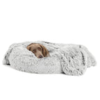 Dog lying on a fluffy gray pet bed against a white background