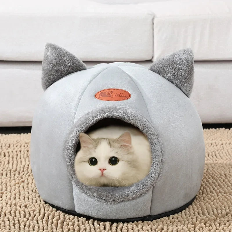 A white and gray cozy cat cave with a cat peeking out from the opening.
