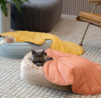 A cat sleeping under yellow leaf-shaped blanket.